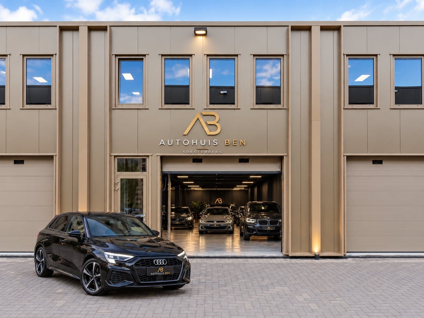 De gevel van Autohuis Ben in Soesterberg, met een zwarte Audi voor de open showroom